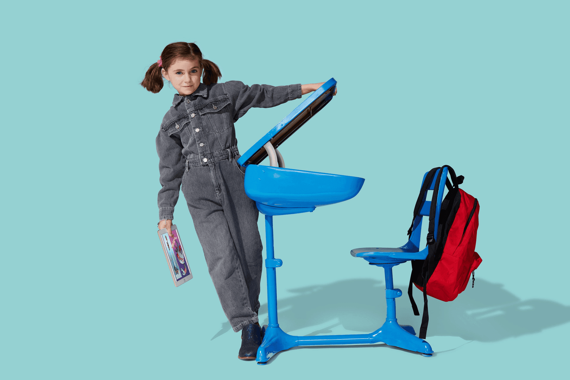 Student leaning on a blue desk against a teal backdrop